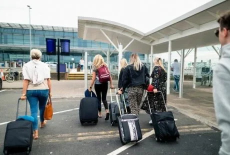 People looking for car service in airport carrying suitcases